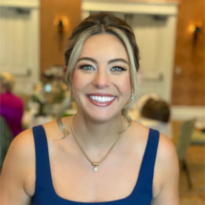 Bridesmaid wearing elegant updo with loose tendrils and classic makeup, showcasing radiant smile in navy dress