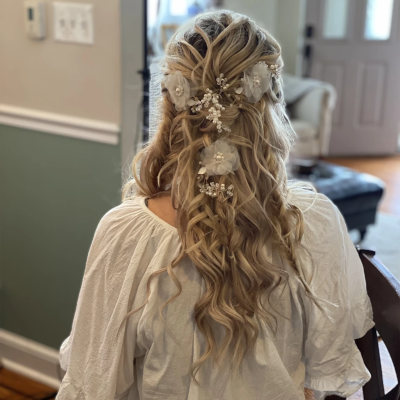Half-up bridal hairstyle with cascading waves and pearl hair accessories, featuring romantic loose curls and delicate floral pins