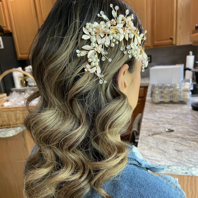 Side-swept bridal waves with delicate floral hair vine, showcasing ash blonde highlights and soft romantic curls